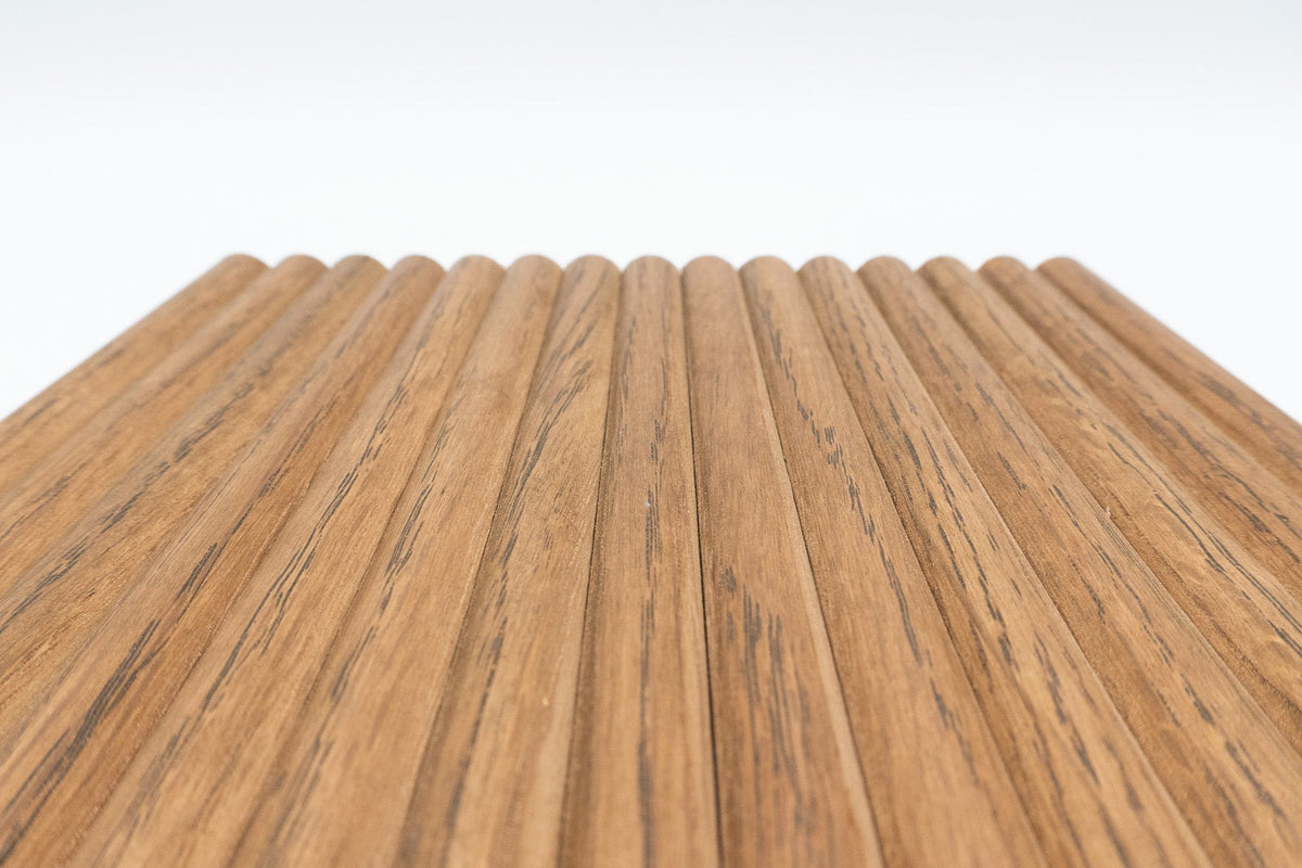 A close-up of a wood-look panel or flooring sample with a repeating wavy profile and visible grain, shown against a clean white background.